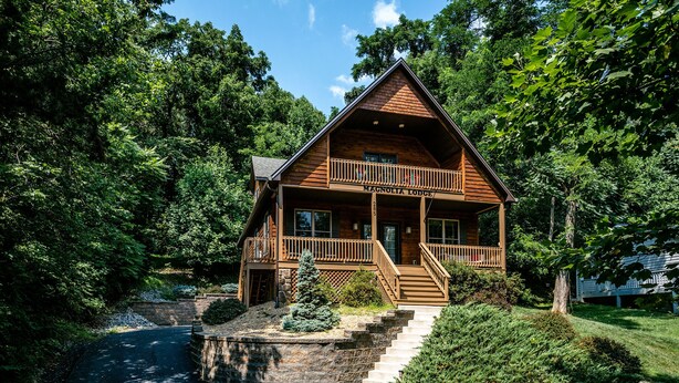 A lodge with a wooden exterior, a balcony, and a stone staircase leading to the entrance. - Sunrise Views & Mountain Charm! (Mc Gaheysville)
