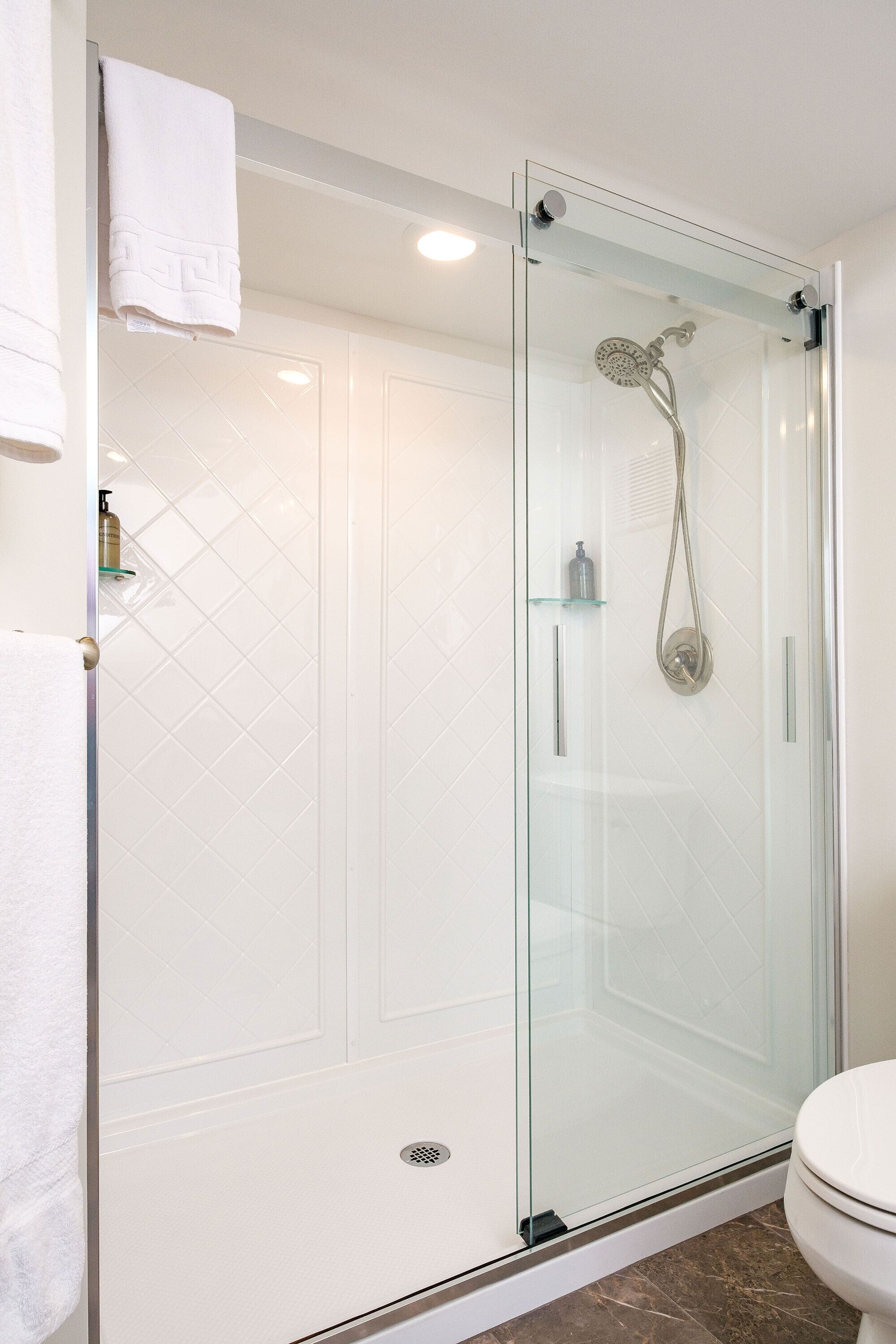 A modern bathroom with a glass-enclosed shower, a toilet, and a towel rack.