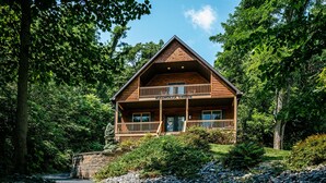 A two-story log cabin with a balcony, surrounded by dense forest. - Sunrise Views & Mountain Charm! (Mc Gaheysville)
