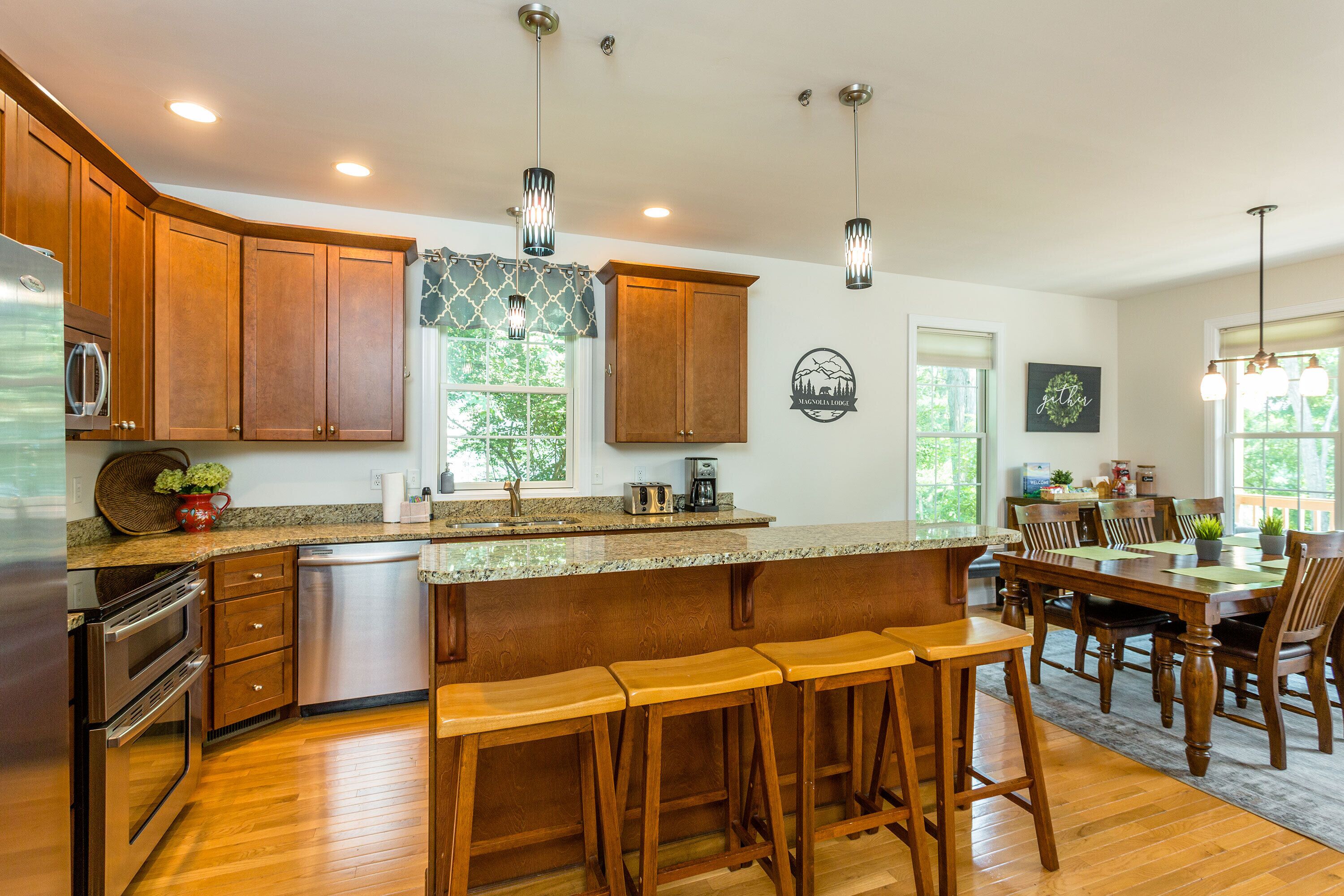 A kitchen with wooden cabinets, a granite countertop, and a bar stool area.