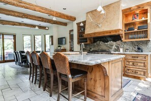 A spacious kitchen with a large island, wooden cabinets, and a stone backsplash.