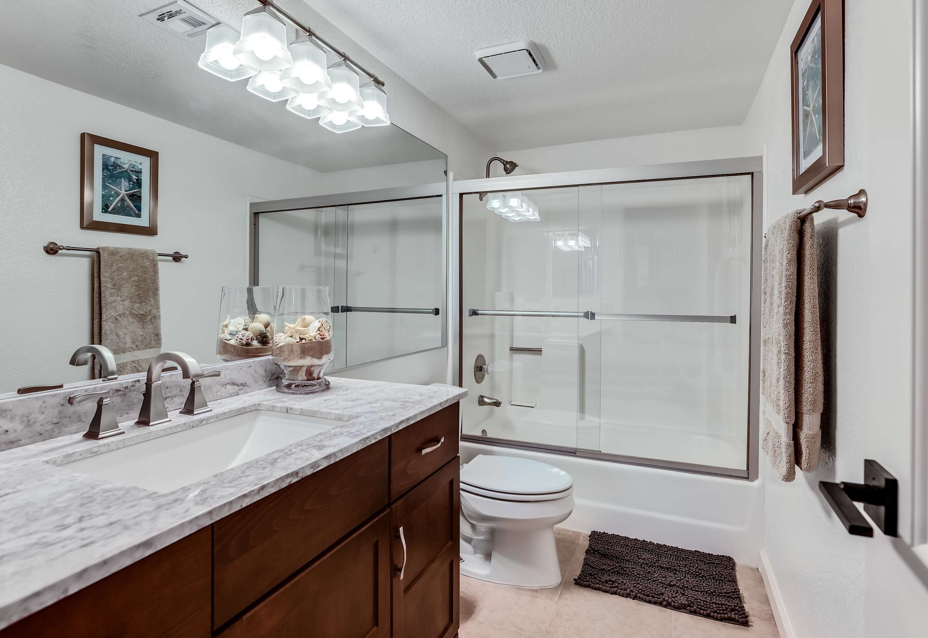 A modern bathroom with a marble sink, a glass shower enclosure, and a white toilet.