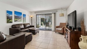 A living room with a sofa set, a television, and a sliding glass door leading to an outdoor area. - 2BR 2BA Stylish Palm Springs Condo (Palm Springs)