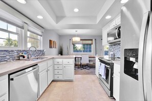 A modern kitchen with white cabinetry, a built-in microwave, and a water dispenser. - Relaxing Palm Springs Condo With Pool Access (Palm Springs)