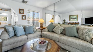 A living room with a sofa set, a coffee table, lamps, and a television. - Stylish Condo With Panoramic View Community Pool (Palm Springs)