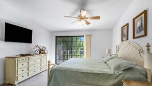 A bedroom with a bed, a dresser, a ceiling fan, a TV, and a window with curtains. - Stylish Condo With Panoramic View Community Pool (Palm Springs)