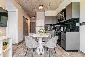 A modern kitchen with grey cabinets, a white dining table with four chairs, and a small plant centerpiece. - w Splendid 1BR in the Heart of Centriqo (Veracruz)