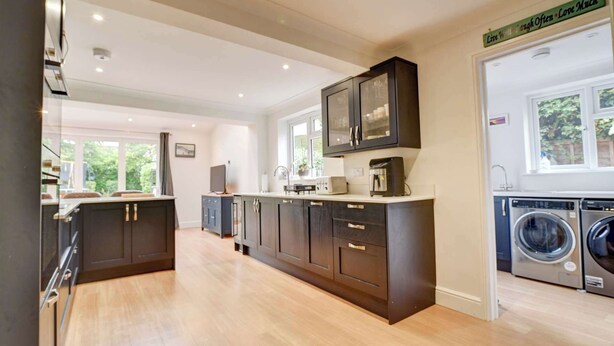 A modern kitchen with dark cabinetry, a central island, and a built-in washing machine area.