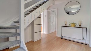 A staircase with a modern design, a white door, and a console table with candles and a plant.