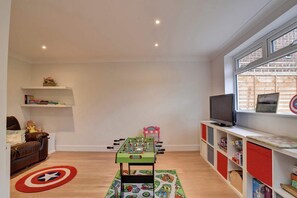 A room with a foosball table, a television, and shelves with books and toys.