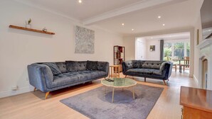 A living room with two dark sofas, a round coffee table, and a bookshelf.