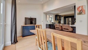 A modern kitchen with a dining area, a TV, and a skylight.