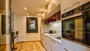 A modern kitchen with a built-in oven, a countertop with a kettle, and a framed artwork on the wall. - Deauville Lovely Flat with Private Garden (Deauville)