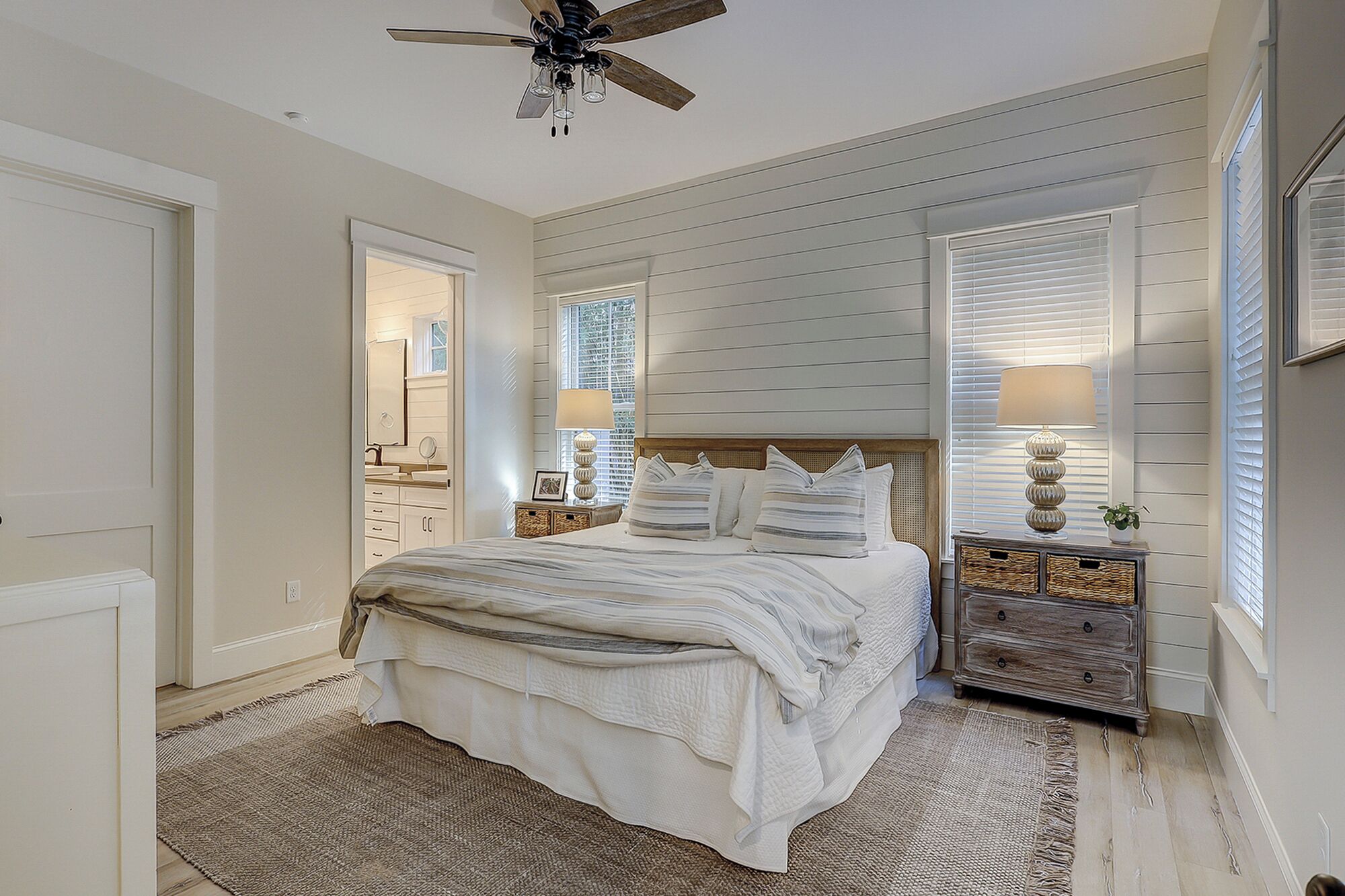 A bedroom with a bed, two nightstands, a ceiling fan, and a window with blinds.