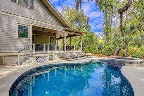 Una casa con piscina, un portico coperto e vista sugli alberi.