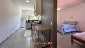 A compact living space with a kitchenette, a dining area, and a bed.