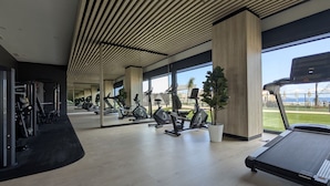 A gym with exercise equipment, large windows, and a view of the outdoors.