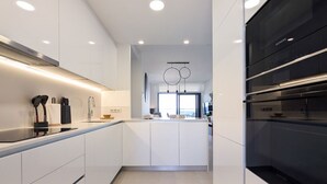 A modern kitchen with white cabinetry, a central island, and built-in appliances.