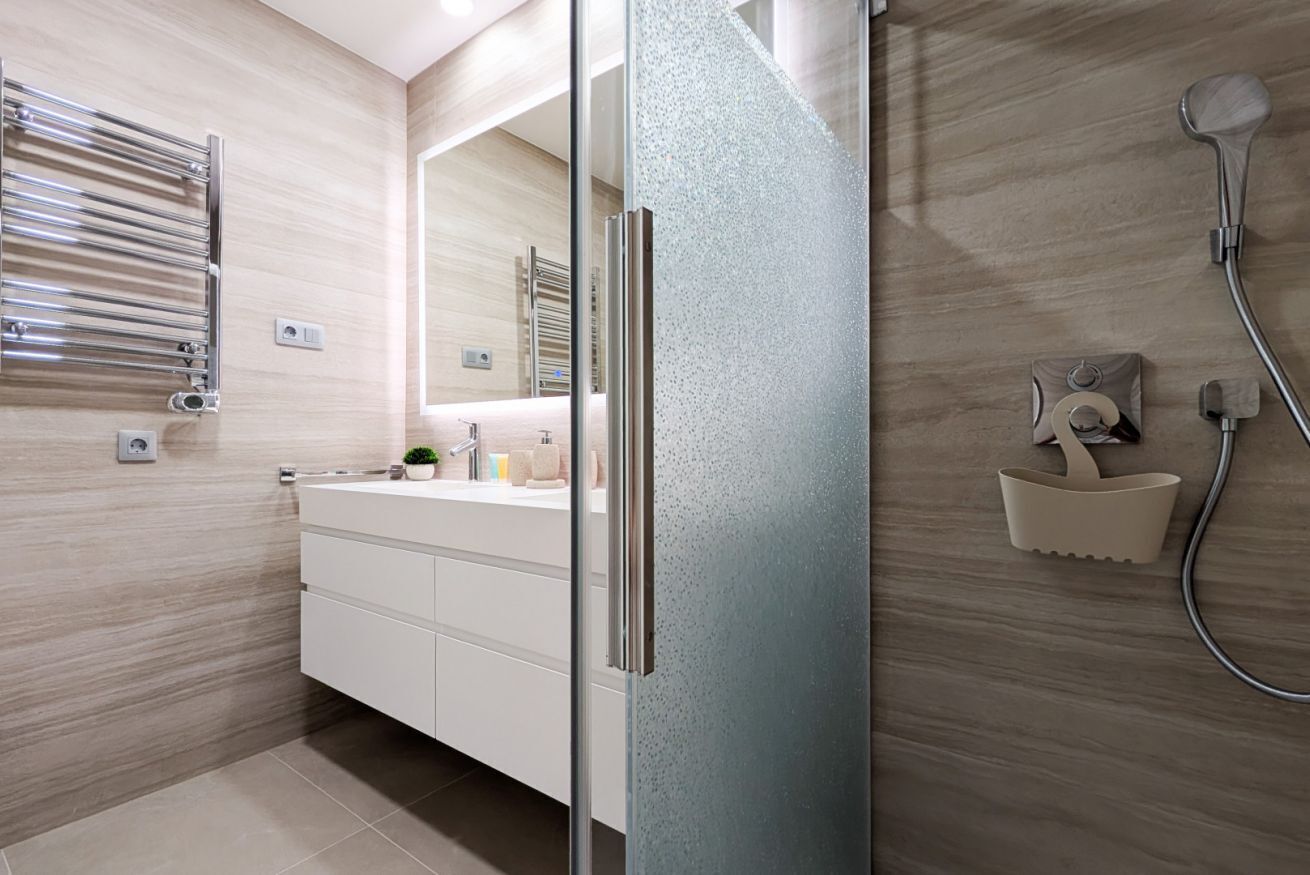 Un bagno moderno con cabina doccia in vetro, mobile lavabo sospeso e portasciugamani.