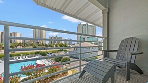 Ein Balkon mit Blick auf einen Swimmingpool, einen Stuhl und eine Skyline mit hohen Gebäuden.