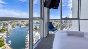 A hotel room with a large window offering a city view, a flat-screen TV mounted on the wall, and a neatly made bed. - Level 30 Renovated Apt with Hot Tub & Netflix (Surfers Paradise)