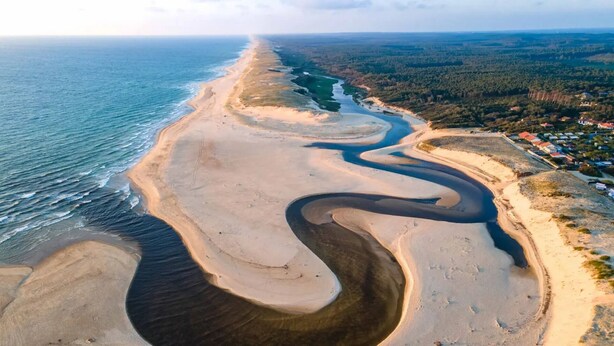 An aerial view of a coastal area with a winding water channel, sandy beaches, and a residential area with houses. - Caban'Océan, the ideal way to discover the Landes Coast between Sea Spray and Pines (Vielle-Saint-Girons)