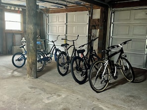 Fietsen staan in een garage met een betonnen vloer en een houten paal.