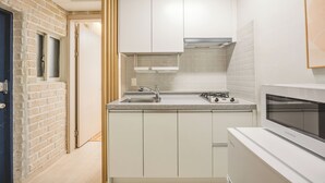 A compact kitchen with white cabinets, a built-in microwave, and a stainless steel sink.