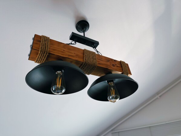 A ceiling light fixture with two bulbs hanging from a wooden beam.