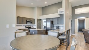 Una cocina moderna con electrodomésticos integrados, un comedor con mesa y sillas redondas, y una zona de estar separada con un sofá.