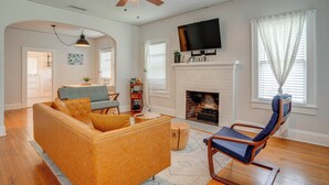 A living room with a sofa, a chair, a fireplace, a television, and a ceiling fan. - Home w/ Private Yard < 2 Mi to Hollis Garden! (Lakeland)