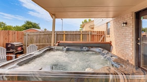 Un bain à remous avec une terrasse en bois et un mur en briques.