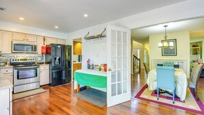 A modern kitchen with stainless steel appliances, wooden flooring, and a dining area with a table and chairs. - Close to Hospital & Dulles: Herndon Townhome (Herndon)