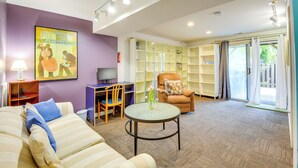 A living room with a sofa, armchair, and a glass coffee table. There is a painting on the wall, a lamp, and a television. - Close to Hospital & Dulles: Herndon Townhome (Herndon)