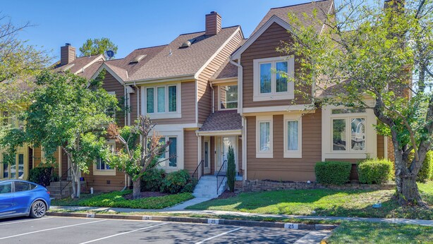 A multi-story residential building with a parking lot and a blue car parked in front. - Close to Hospital & Dulles: Herndon Townhome (Herndon)