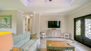 A living room with a sofa, a coffee table, a TV, and a cabinet. - Golf Days & Beach Fun: Port Charlotte Home w/ Yard (Port Charlotte)