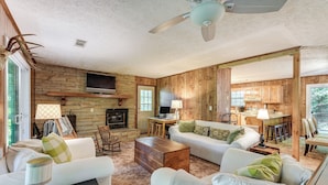 A cozy cabin interior with a fireplace, wooden walls, a dining area, and a kitchen. - Hiwassee River Gem w/ Huge Decks: Great for Groups (Hiawassee)