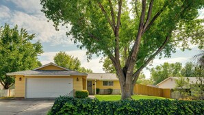 A single-story house with a garage, surrounded by a well-maintained lawn and a hedge. - Quiet & Convenient Sparks Retreat Near I-80 & Reno (Sparks)