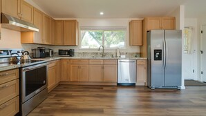 A modern kitchen with wooden cabinets, stainless steel appliances, and a large window. - Quiet & Convenient Sparks Retreat Near I-80 & Reno (Sparks)