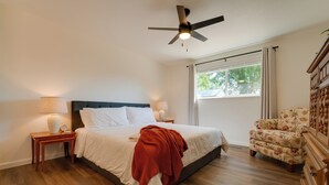 A bedroom with a bed, a nightstand, a chair, a ceiling fan, and a window. - Quiet & Convenient Sparks Retreat Near I-80 & Reno (Sparks)