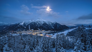 Paisagem montanhosa coberta de neve, com uma cidade no vale abaixo.