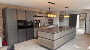 A modern kitchen with a central island, built-in appliances, and pendant lighting. - The Alpine No 7 (Reith bei Seefeld)