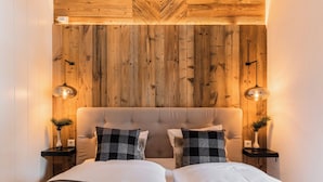 A bedroom with a wooden headboard, two bedside tables with lamps, and a bed with a grey blanket. - The Alpine No 7 (Reith bei Seefeld)