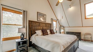 Ein Schlafzimmer mit einem großen Bett, einem Holzkopfende und Blick ins Freie durch ein Fenster.