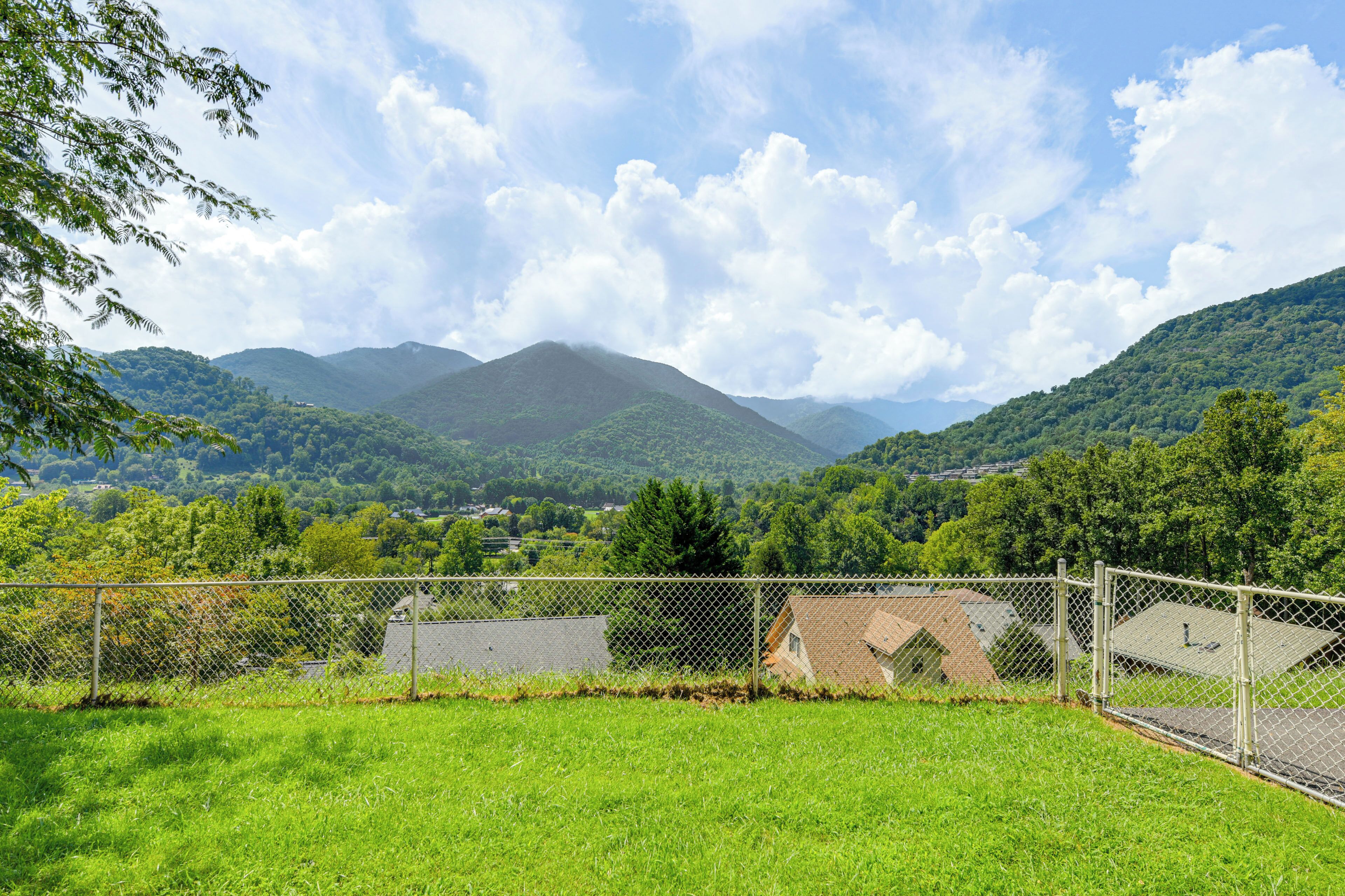 A fenced property with a view of green hills and a mountain in the distance.