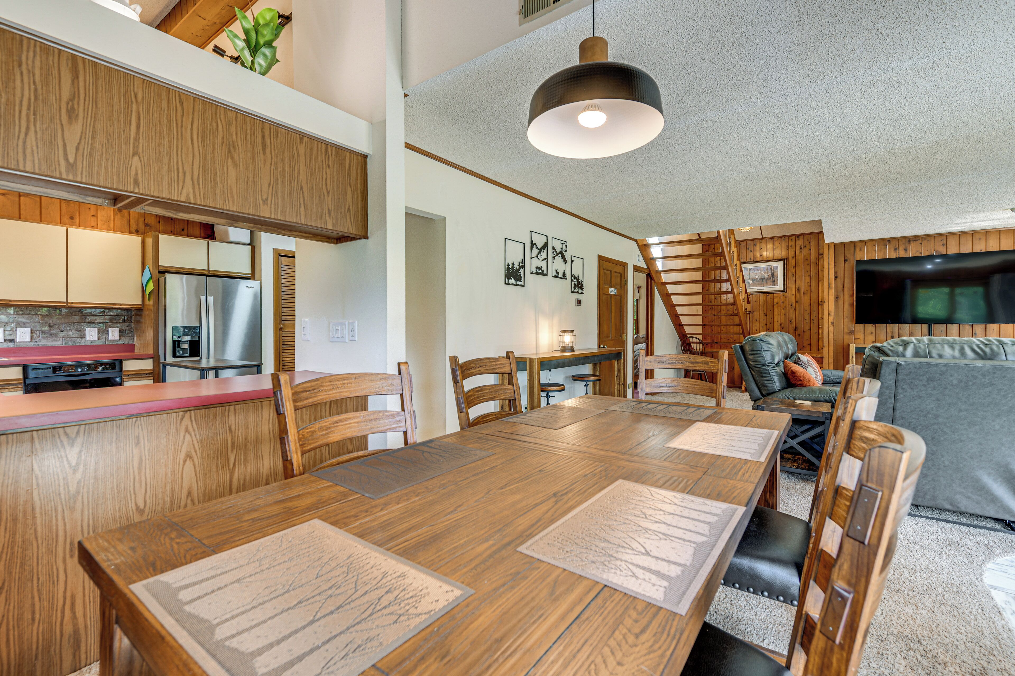 A spacious kitchen with wooden cabinets, a stainless steel refrigerator, and a dining area with a large wooden table and chairs.