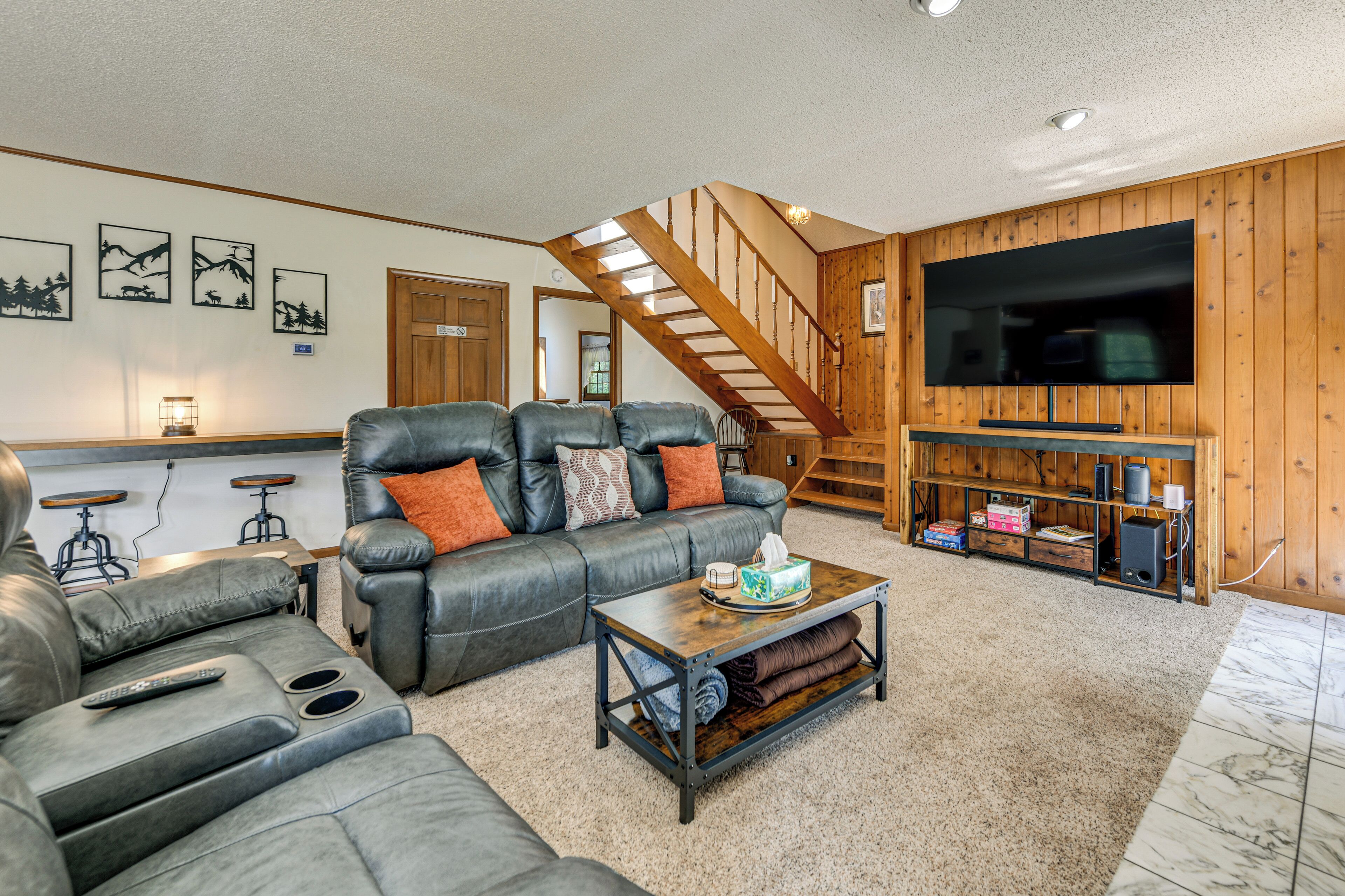 A living room with a sofa, coffee table, and a TV mounted on a wooden wall.