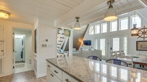 A kitchen with white cabinetry, a granite countertop, and a view of a dining area with a table and chairs.