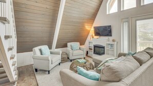 A loft-style living room with a sloped ceiling, built-in seating, a fireplace, and a television.