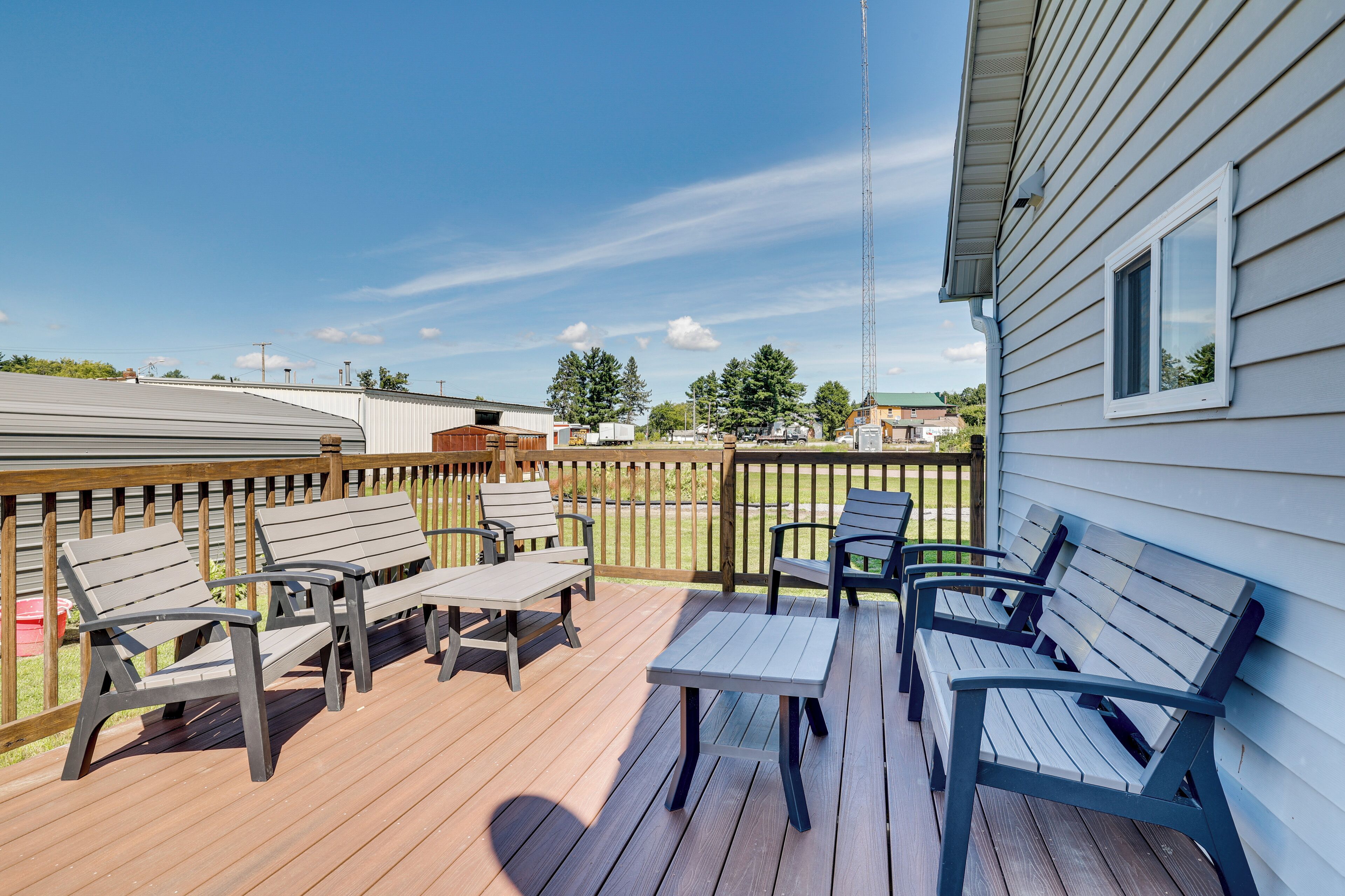 A wooden deck with outdoor furniture, including benches and tables, and a view of the surrounding area.